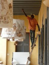 A man up a ladder hanging lamp shades