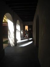 A dark hall way with arches letting in light on one side
