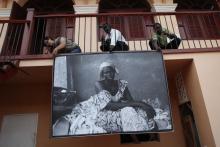 3 people hanging a painting from a balcony
