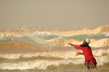 A woman casting a net into the ocean