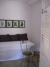 A table and chair at the foot of a white bed