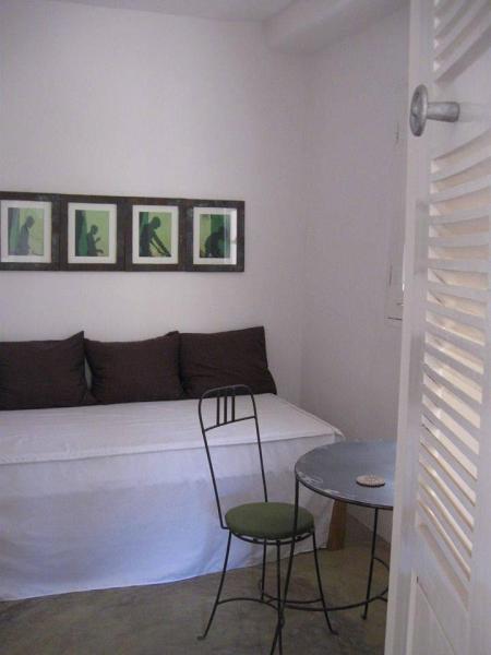 A table and chair at the foot of a white bed